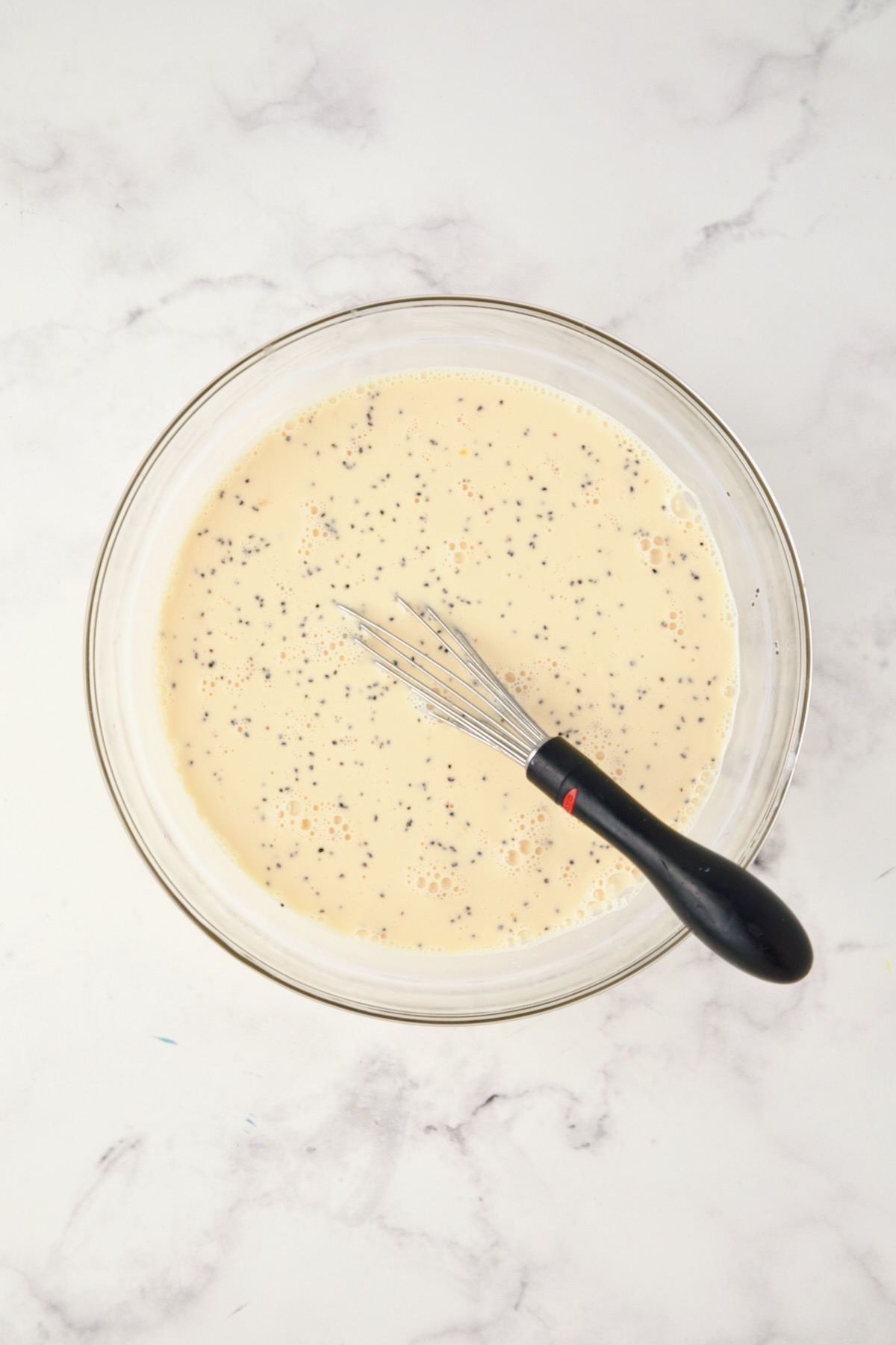 Custard for strata in glass bowl with black-handled whisk.