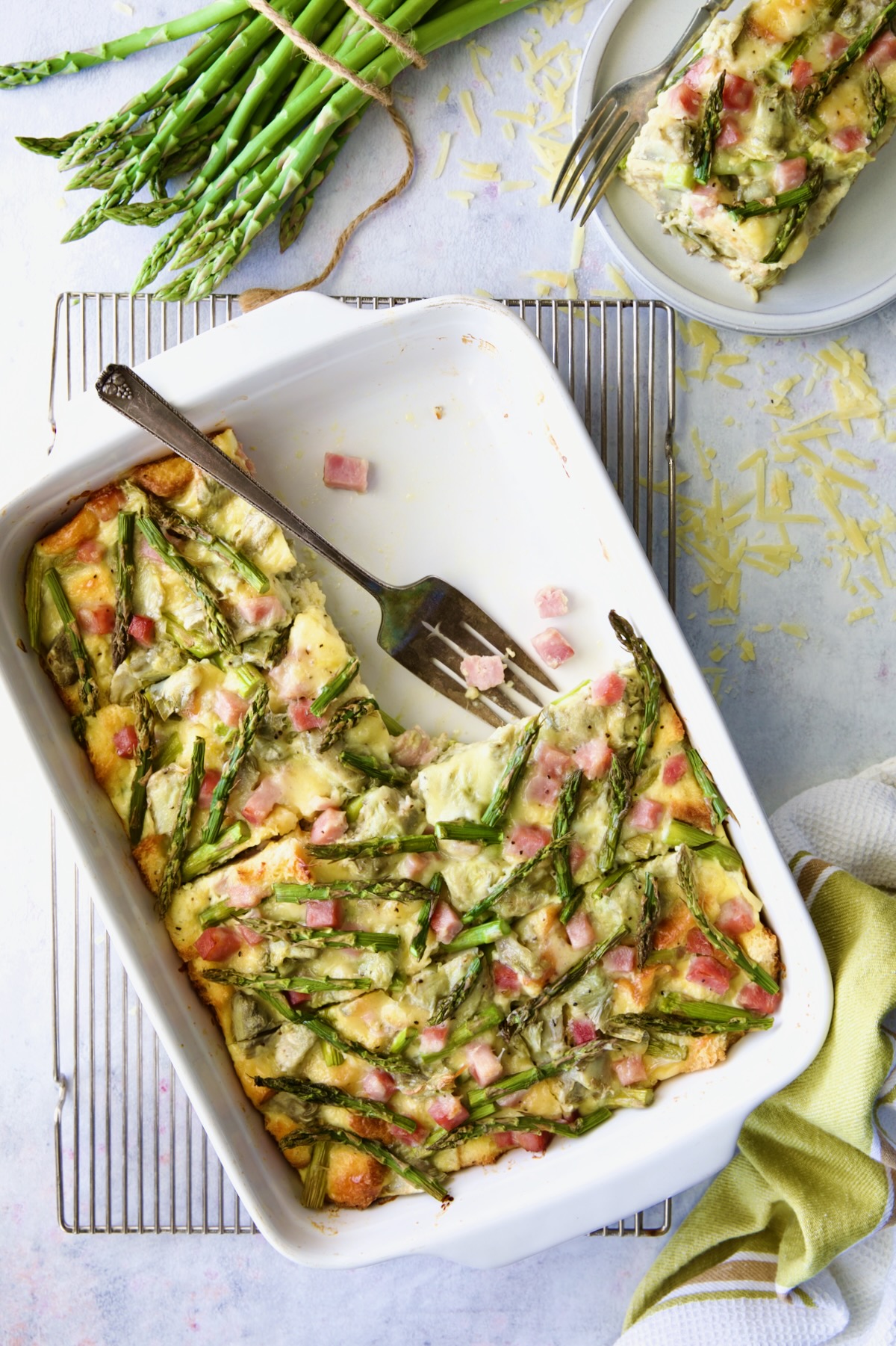 Brioche Breakfast Strata cut into pieces in white rectangular baking dish with two pieces missing.