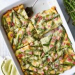 Brioche Breakfast Strata in white rectangular baking dish cut into pieces with one piece missing.