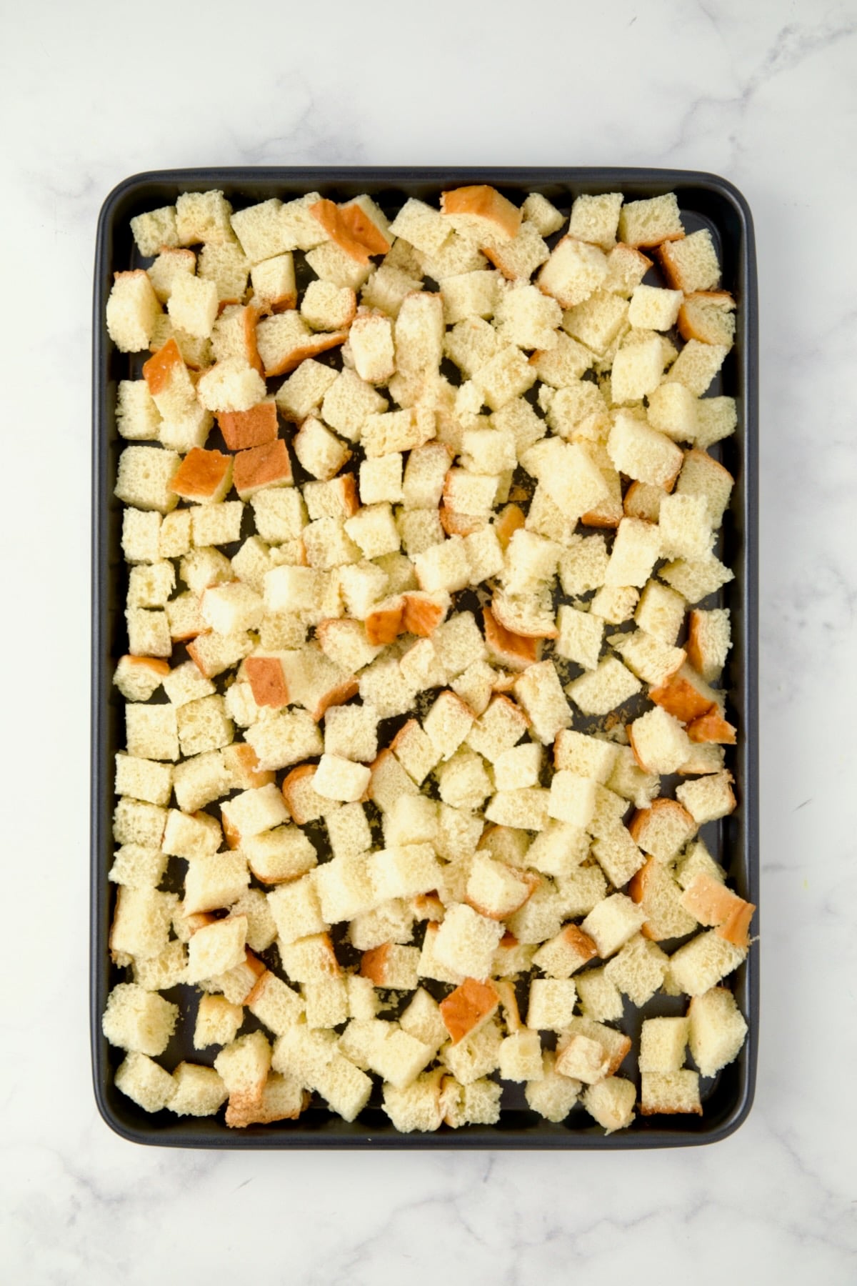 Cubed brioche on rimmed sheet pan before being baked.
