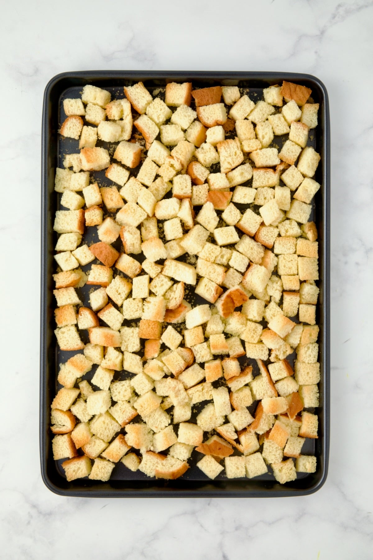 Cubed brioche on rimmed sheet pan after being baked.