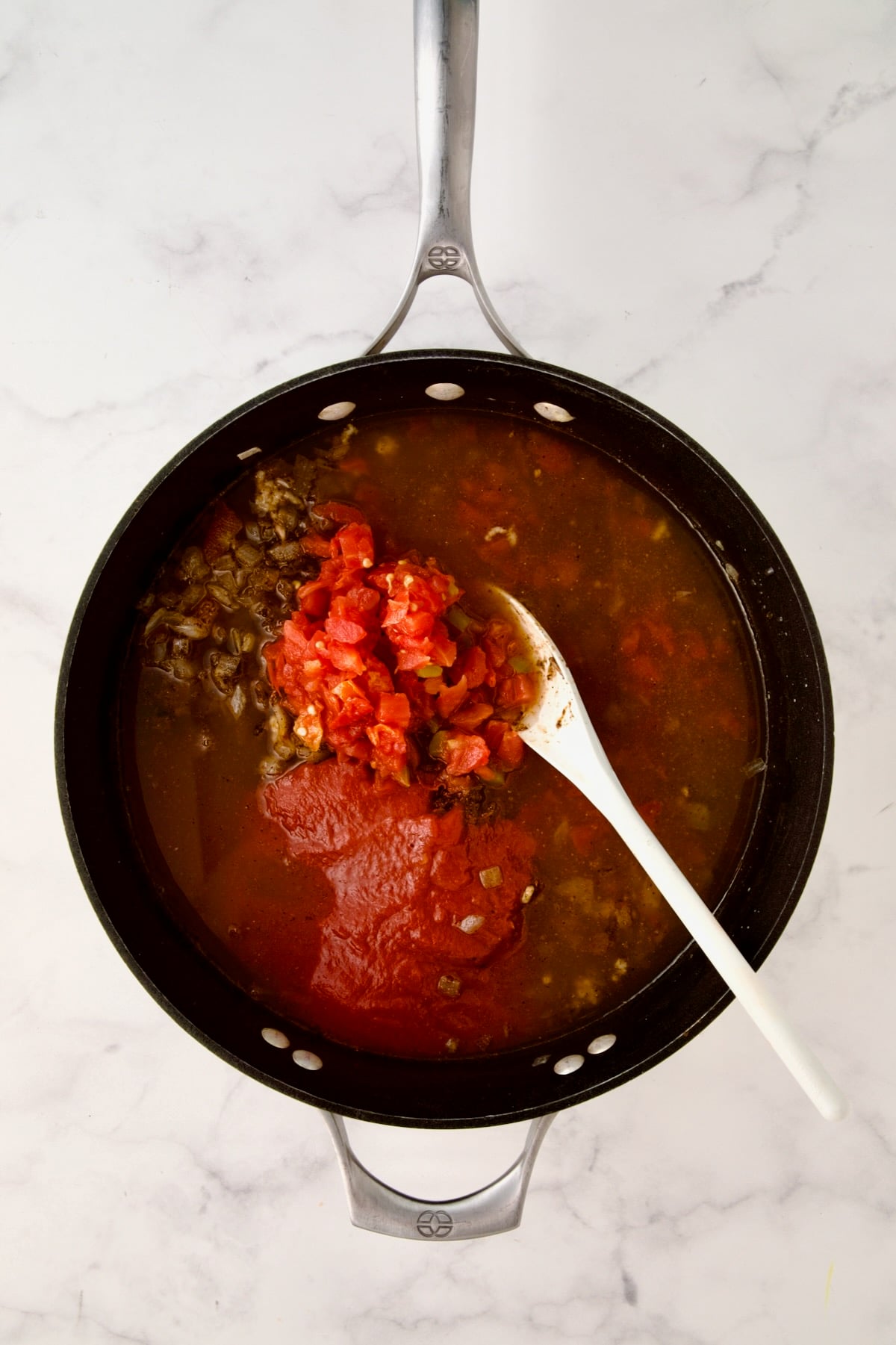 Diced tomatoes, sauce and vegetable broth added to cooked onions and spices in nonstick skillet.