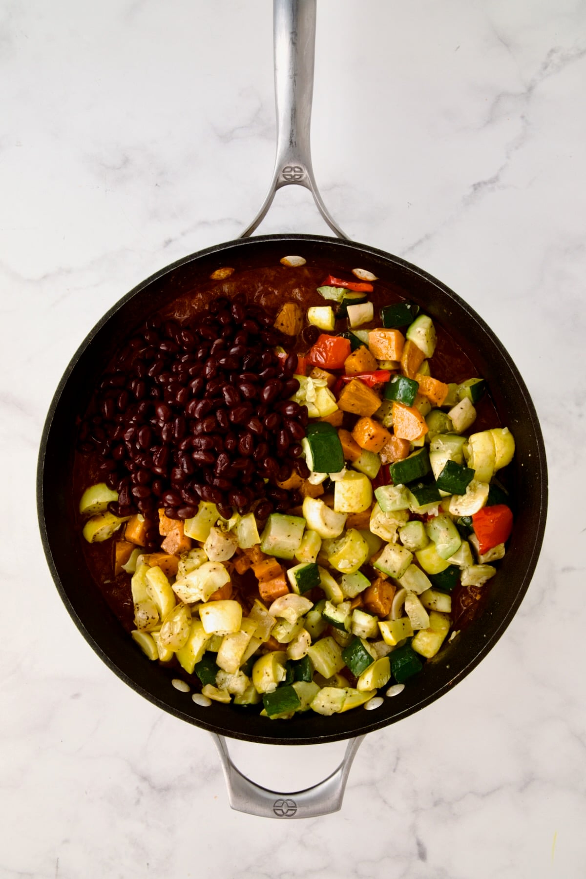 Black beans and roasted vegetables added to stew base in nonstick skillet.