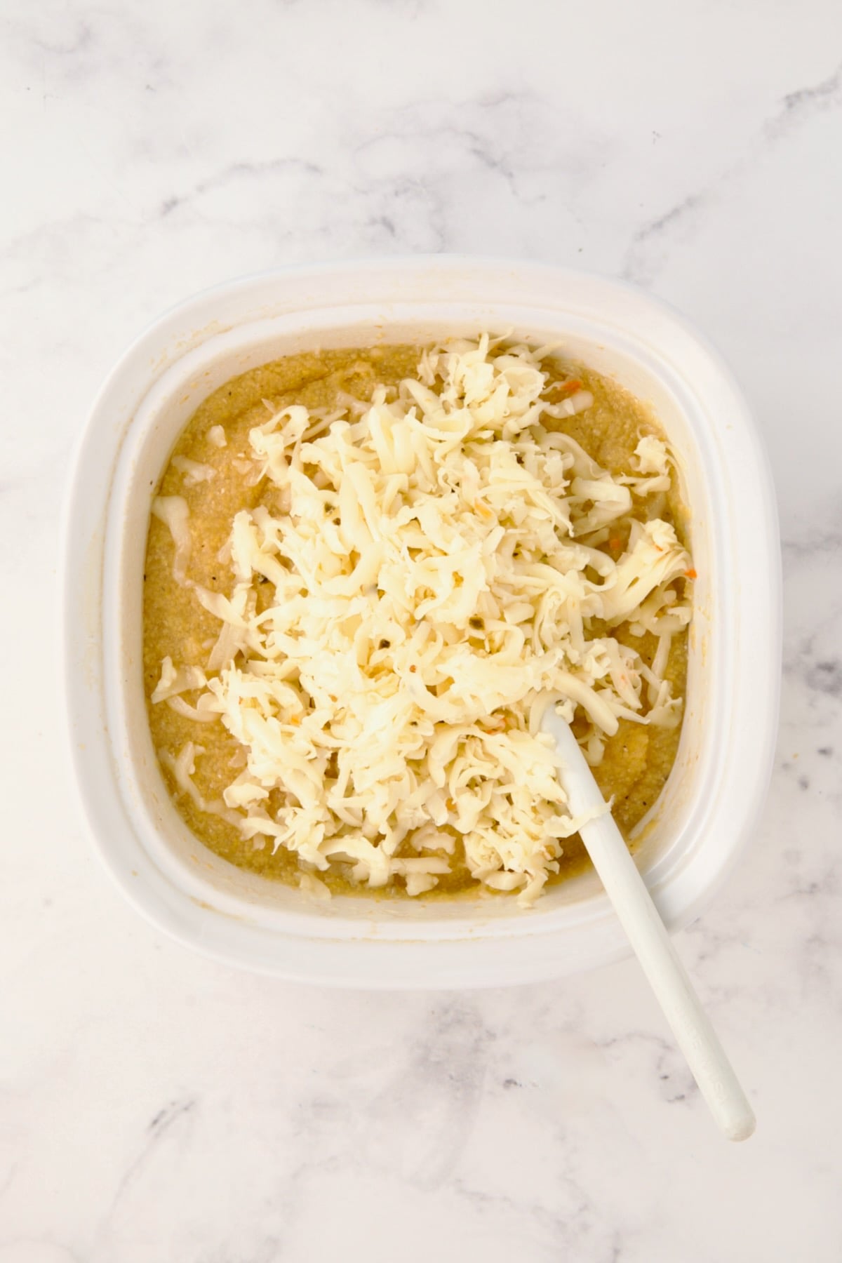 Cheese added to polenta in Corningware dish.
