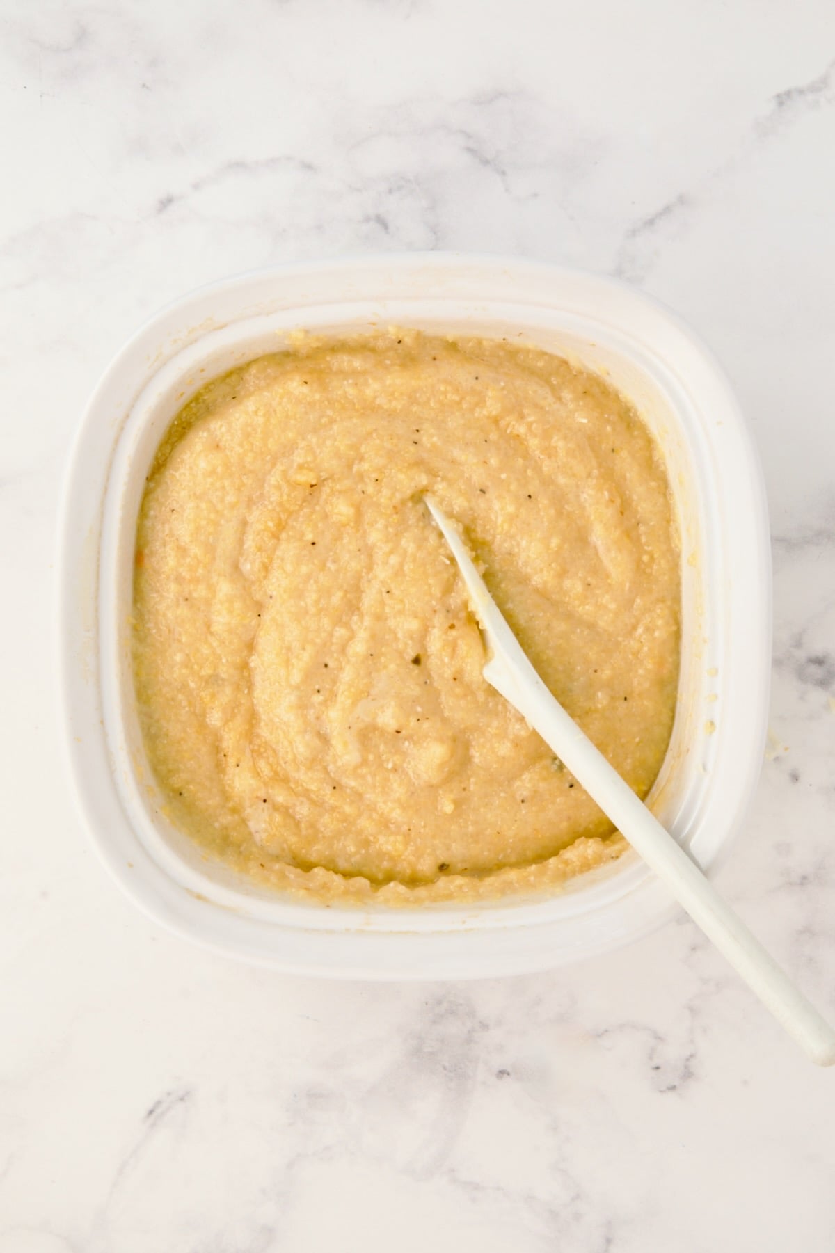 Cooked polenta in white Corningware dish.