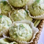 Pile of Dill Zucchini and Ricotta Muffins on square rattan basket.