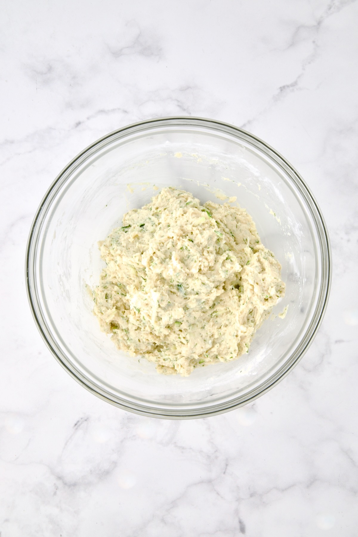 Wet and dry ingredients for muffins combined in glass bowl.