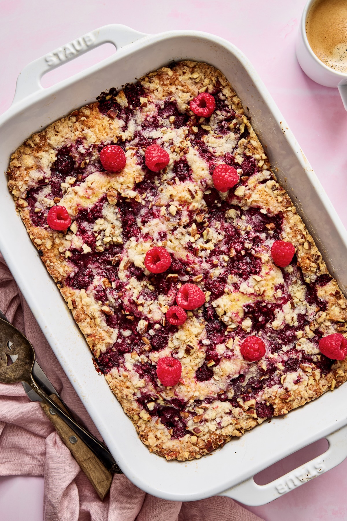 Baked Easy Raspberry Coffee Cake in white rectangular baking dish garnished with fresh raspberries.