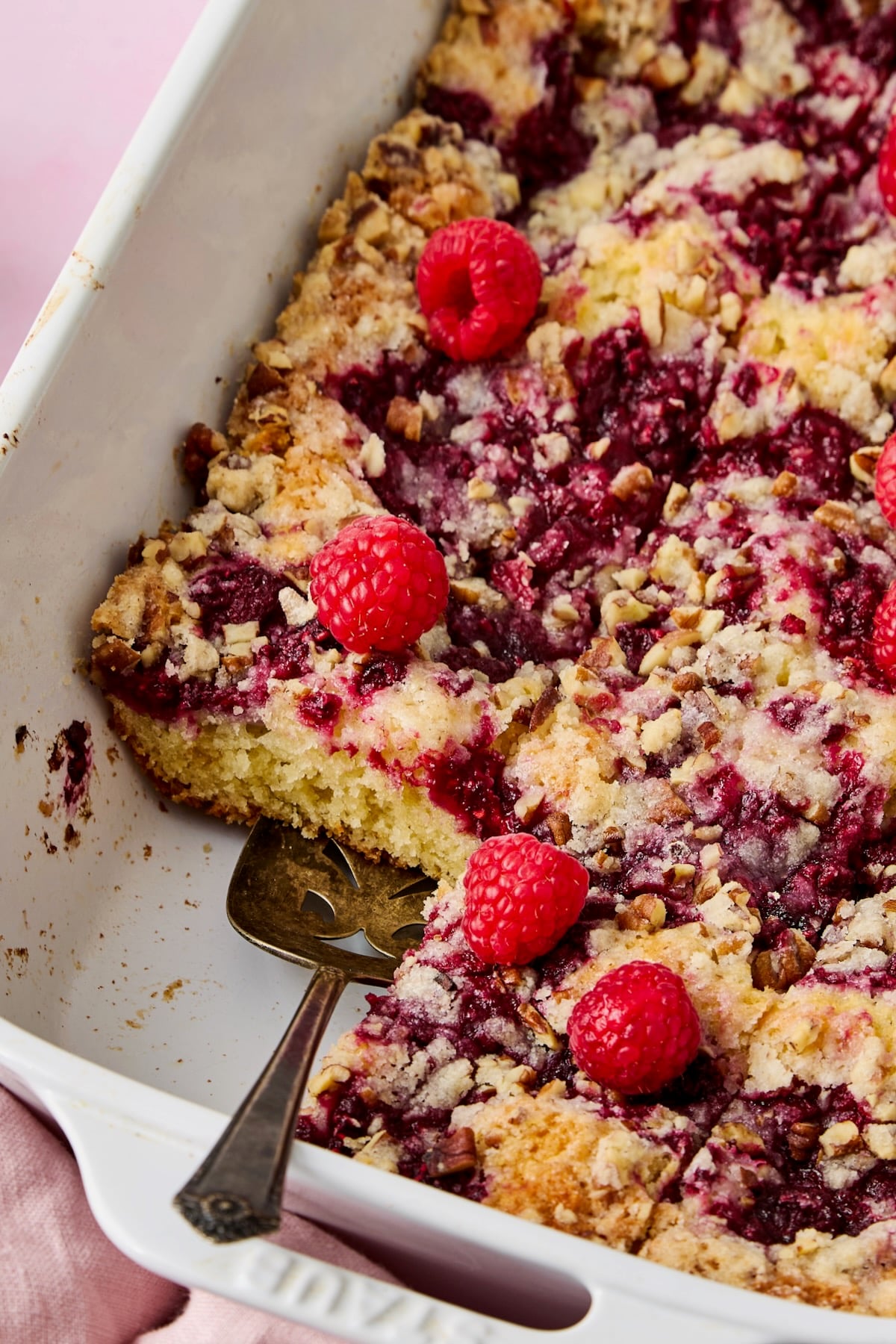 Easy Raspberry Coffee Cake cut into pieces with pie server picking one up.