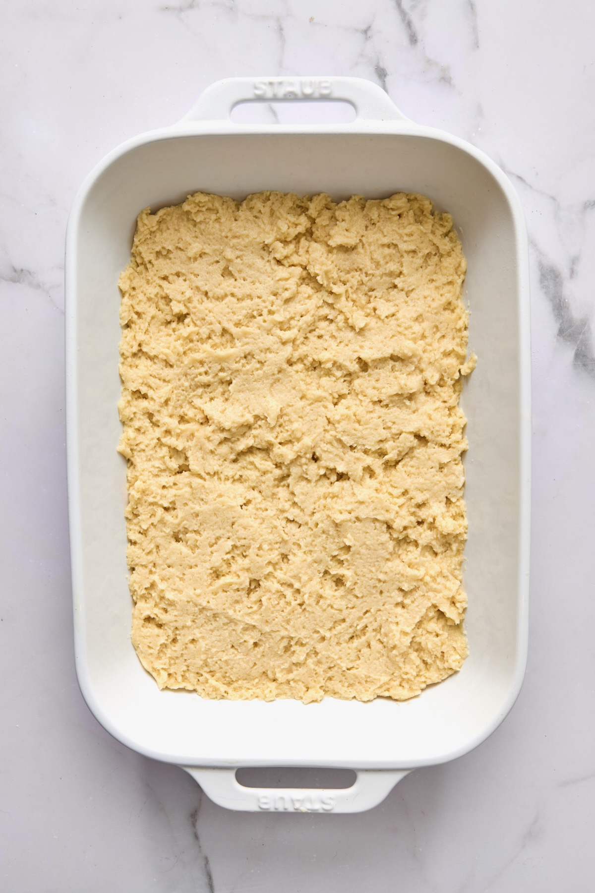 Batter for coffee cake spread into a white rectangular baking dish.