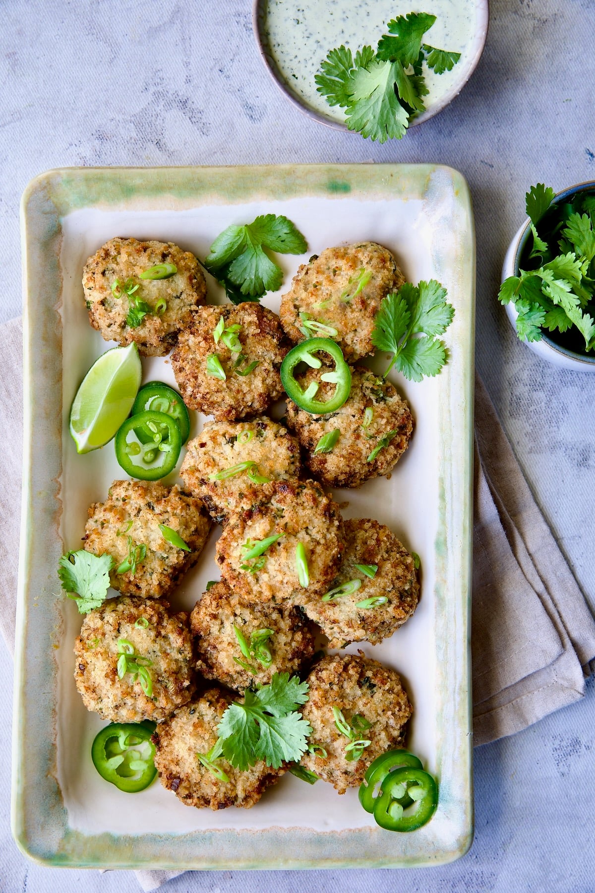 Thai Green Curry Shrimp Cakes on rectangular platter garnished with jalapeno slices and cilantro leaves.