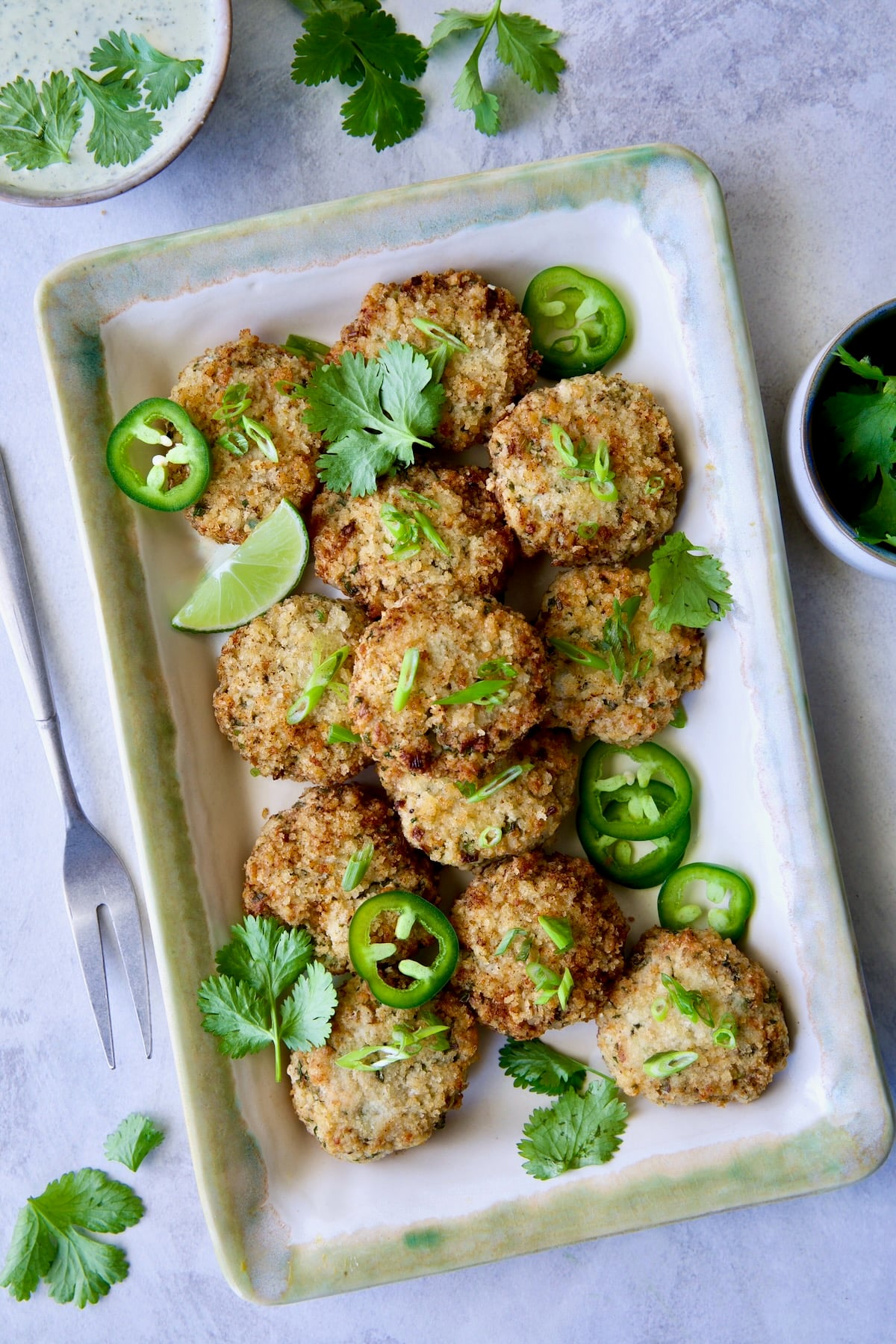 Thai Green Curry Shrimp Cakes on rectangular platter garnished with jalapeno slices and cilantro leaves.