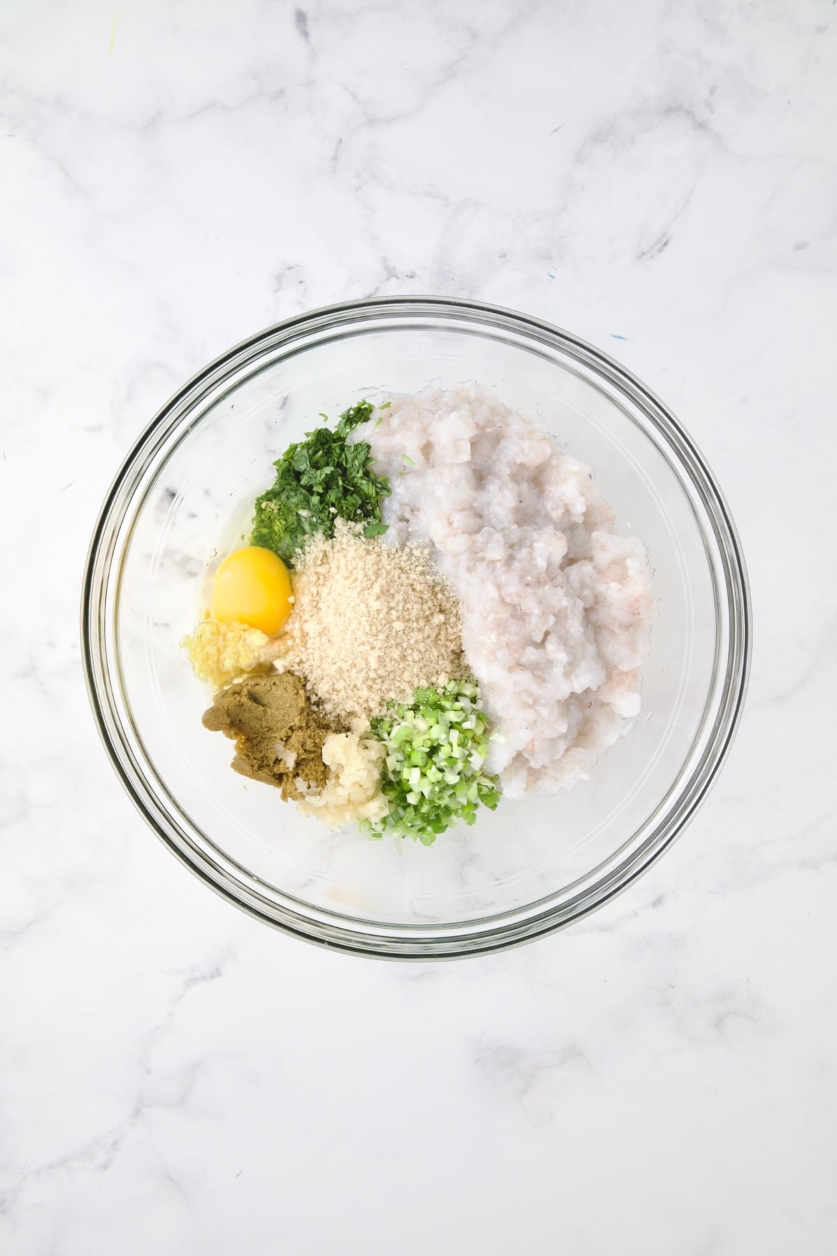 Ingredients for shrimp cakes in glass bowl before being combined.