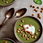 Three bowls of Cream of Spinach Soup garnished with Greek yogurt and roasted chickpeas.