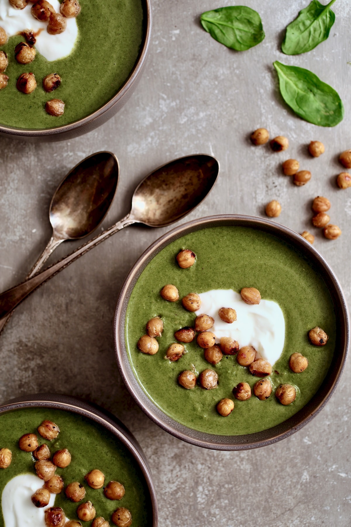 Three bowls of Cream of Spinach Soup garnished with Greek yogurt and roasted chickpeas.