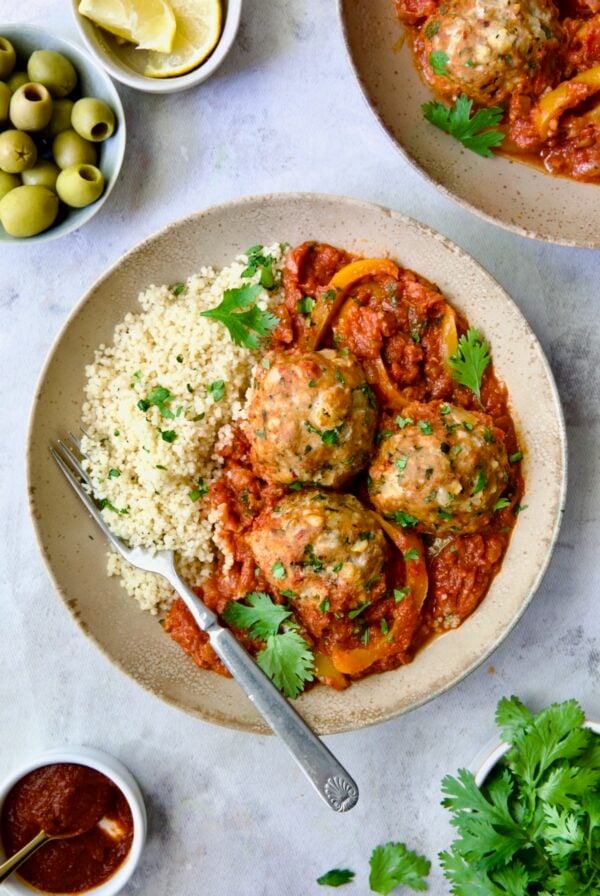 Three Harissa Chicken Meatballs with couscous in earthenware bowl.