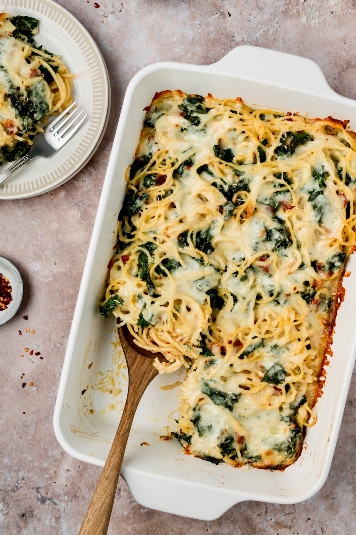 Pasta Frittata in white rectangular baking dish with a piece removed to a white plate.