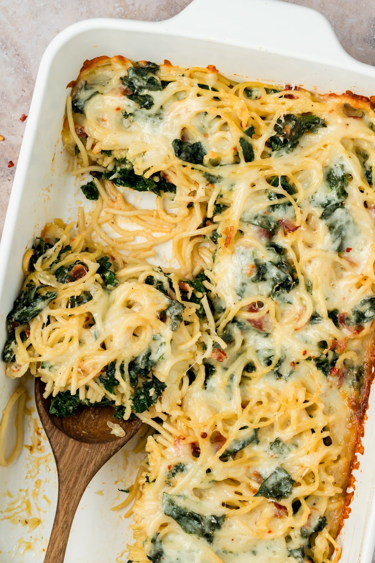Close-up of frittata with wooden spoon lifting a piece out.