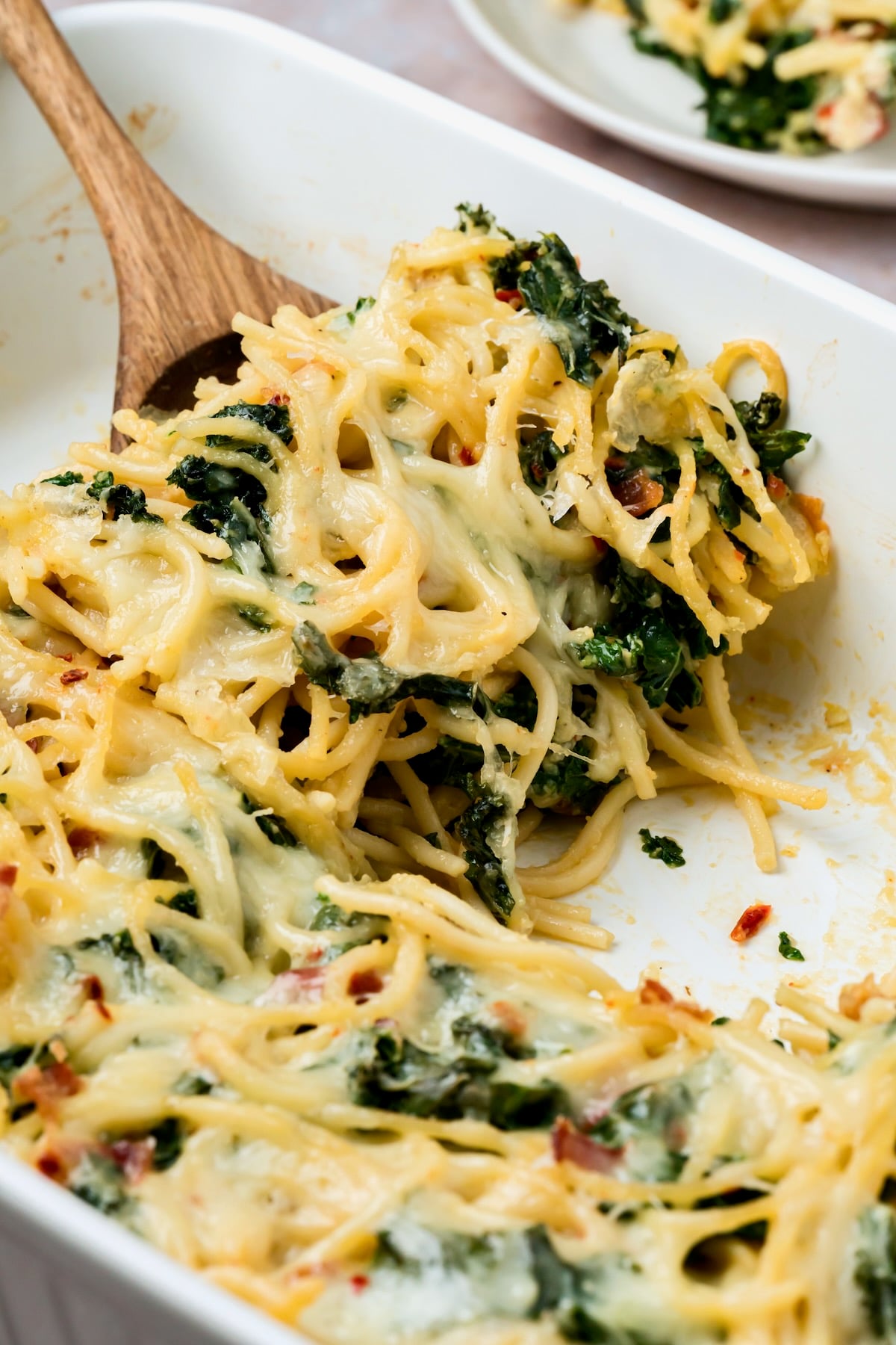 Close-up of frittata with wooden spoon lifting a piece out.