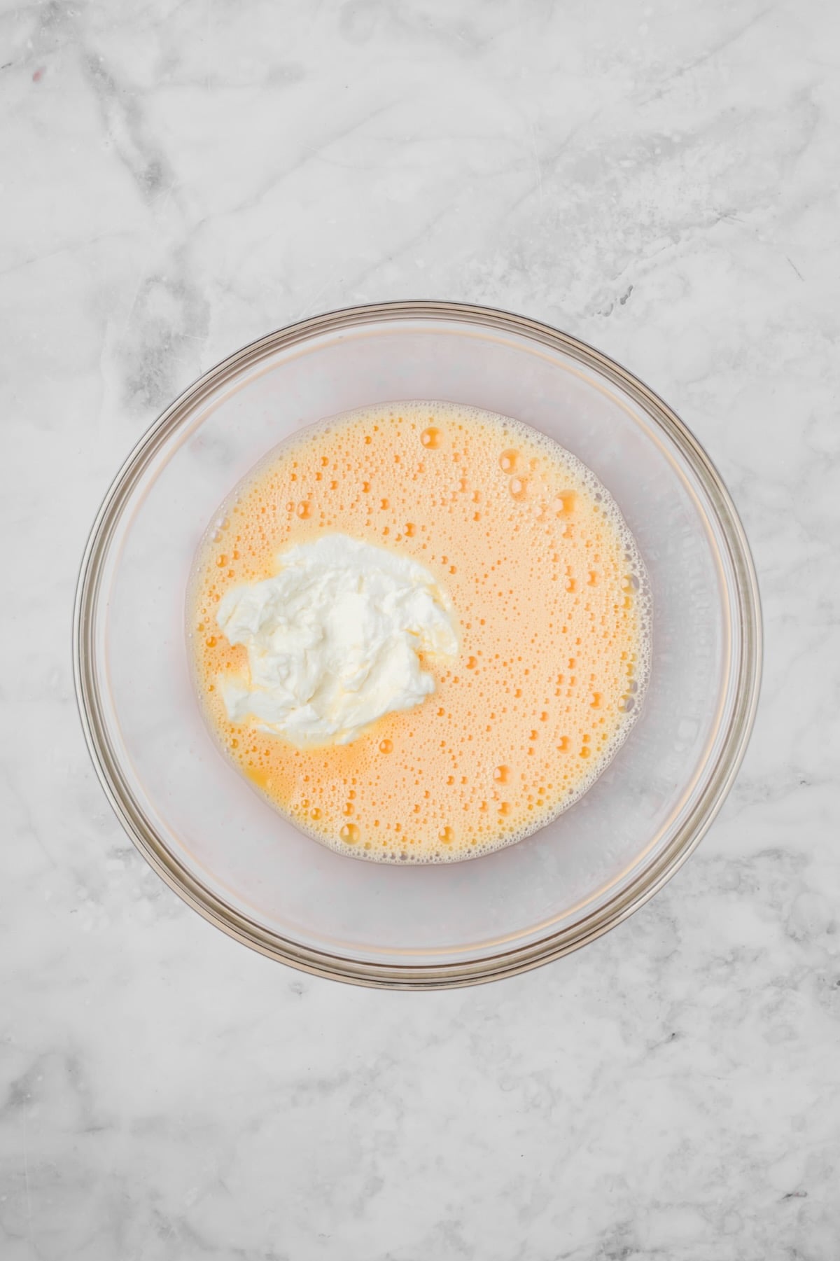 Beaten eggs in glass bowl with ricotta cheese added.
