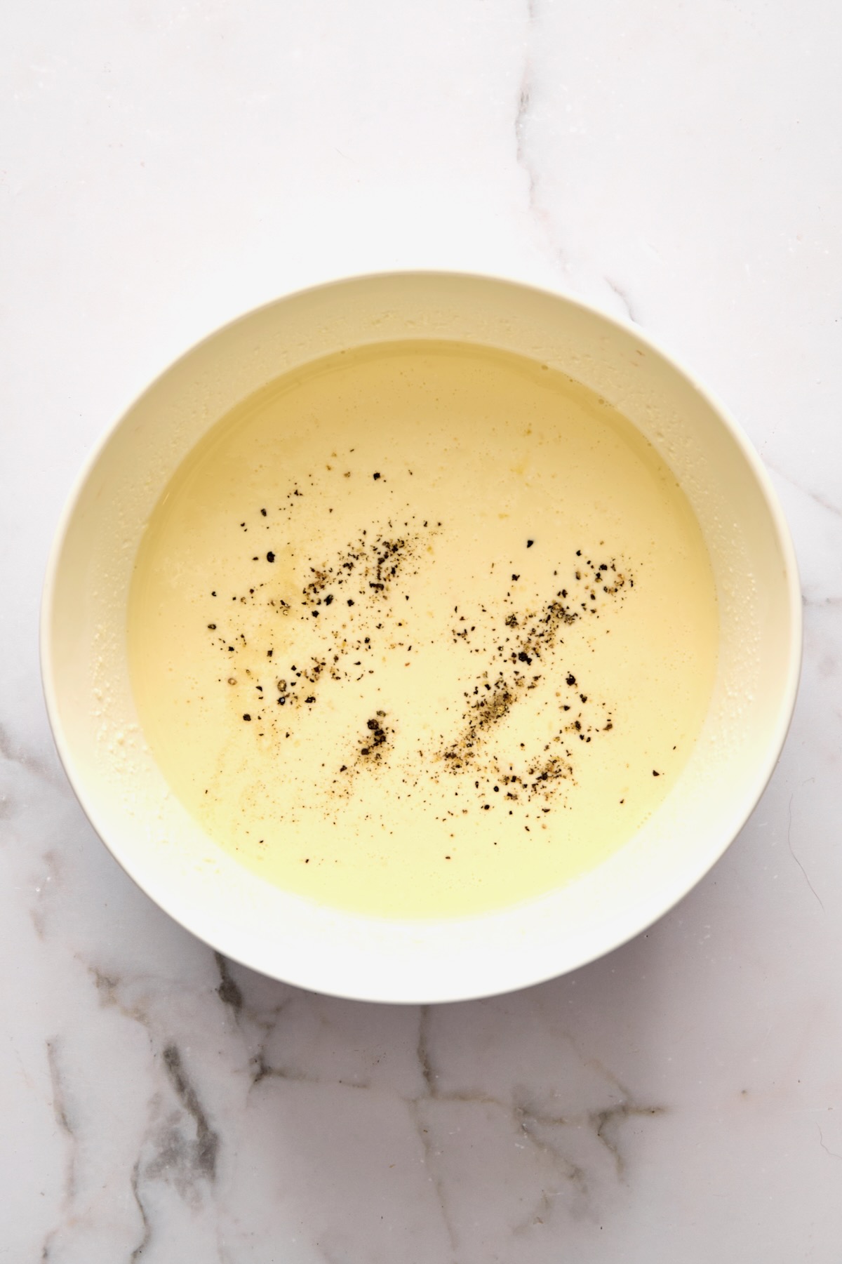 Custard for quiche in white mixing bowl.
