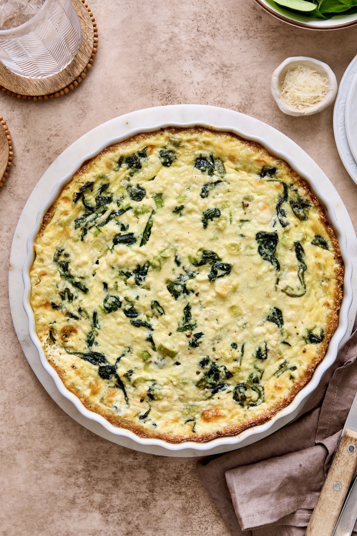 Baked Spinach Feta Quiche with Quinoa Crust in round white baking dish.