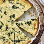 Spinach Feta Quiche with Quinoa Crust in white round baking dish cut into pieces.