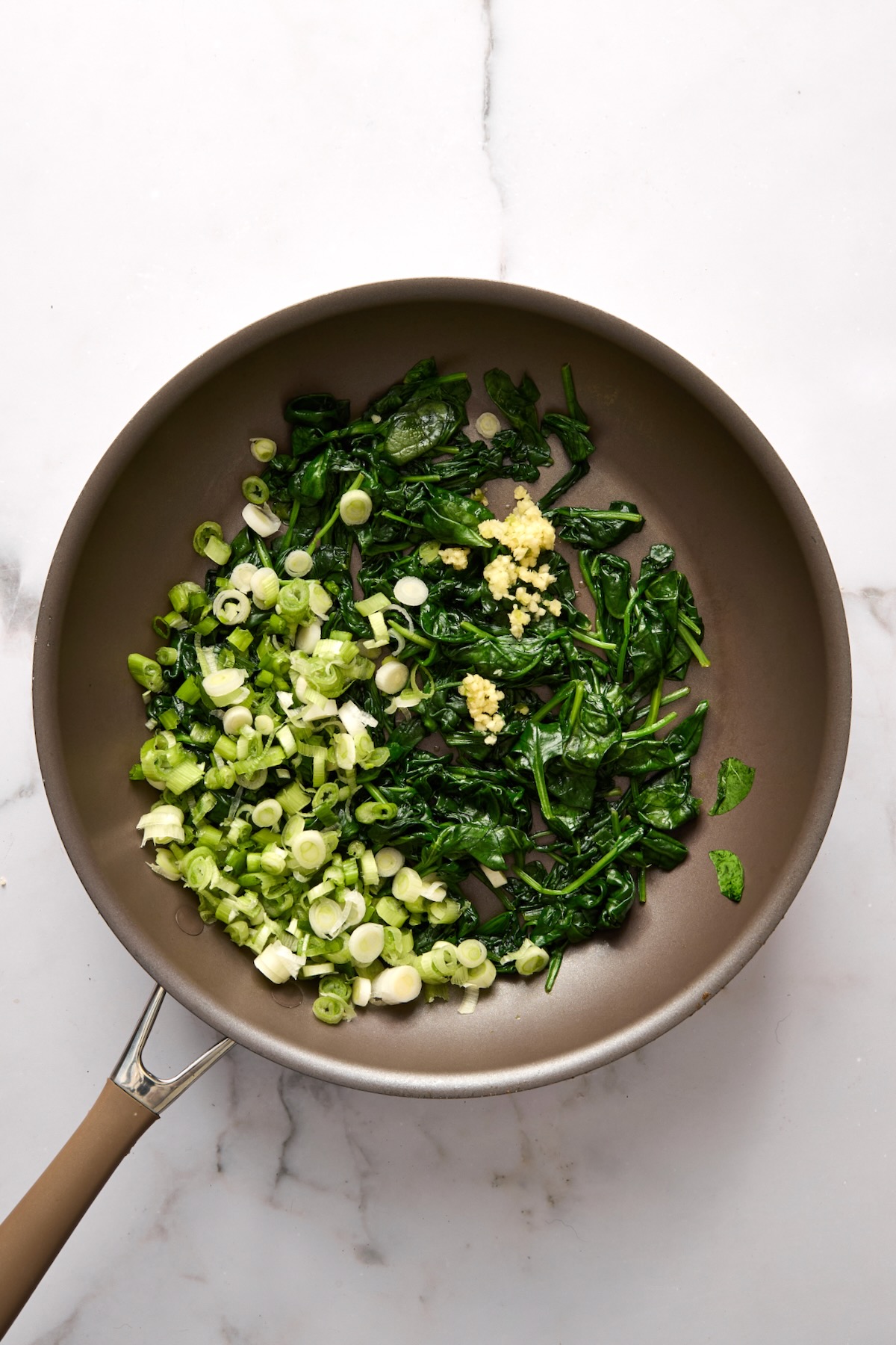Cooked spinach and scallions in saute pan.