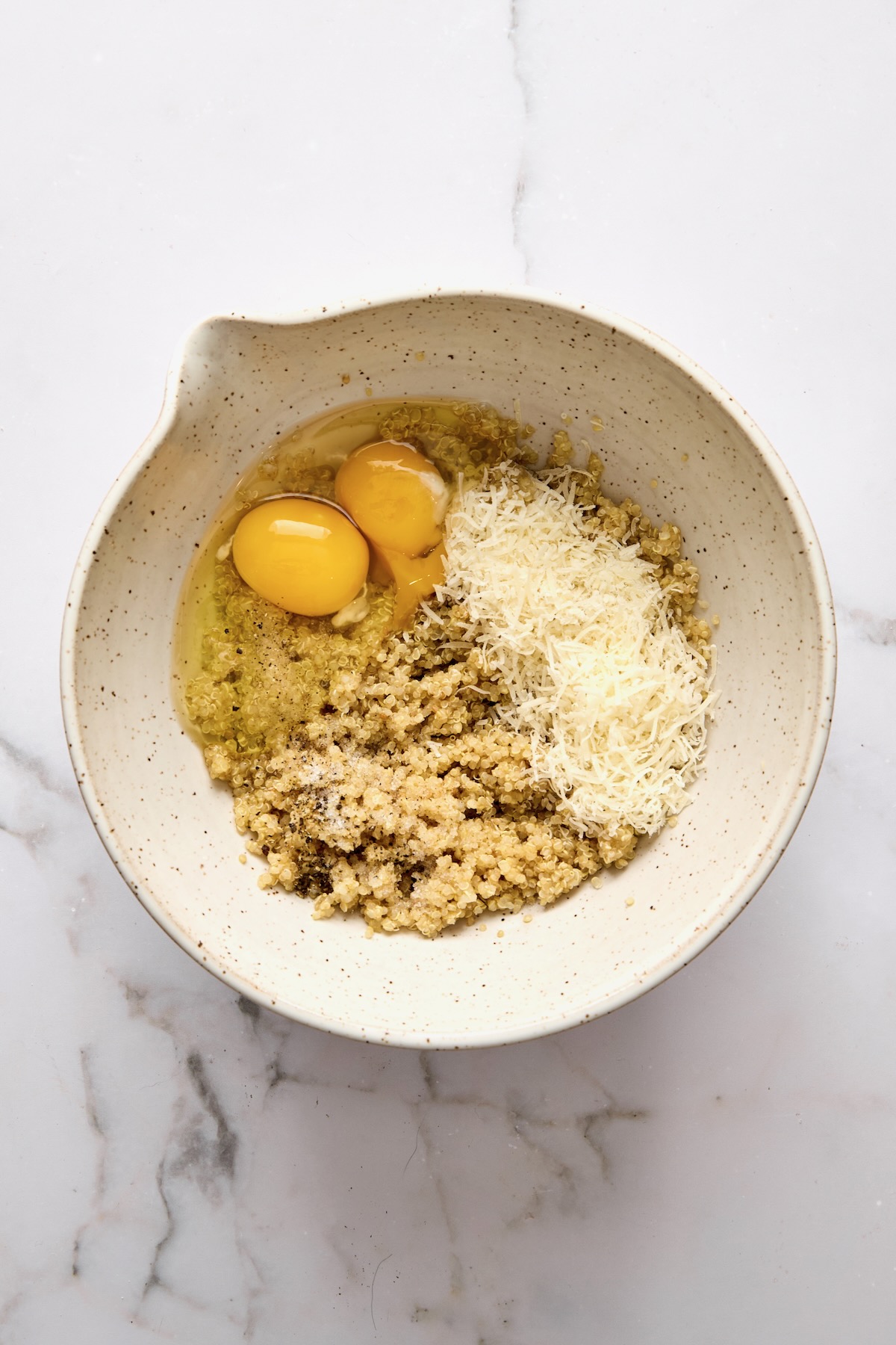 Cooked quinoa, eggs, and cheese in mixing bowl.