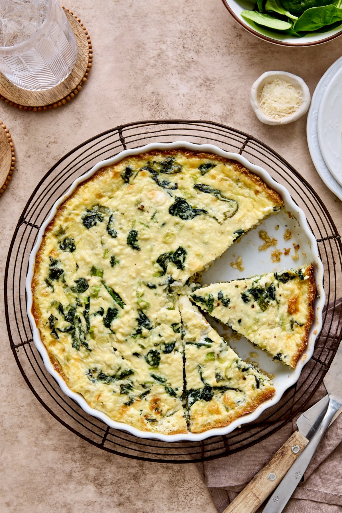 Spinach Feta Quiche with Quinoa Crust in white round baking dish cut into pieces.