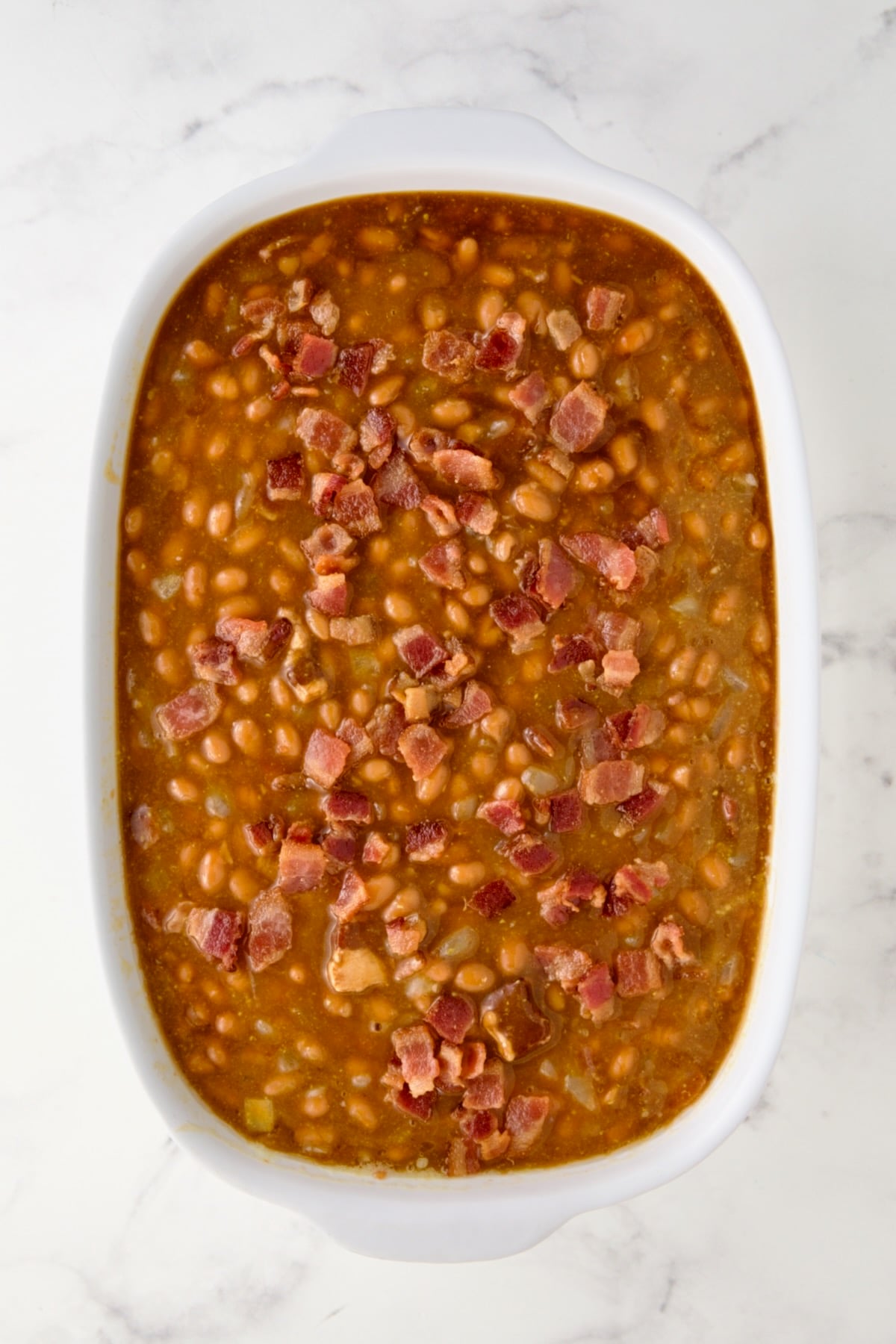 Baked beans with ingredients added and bacon sprinkled over the top.