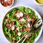 French Lentil Salad in white serving bowl with serving utensils.