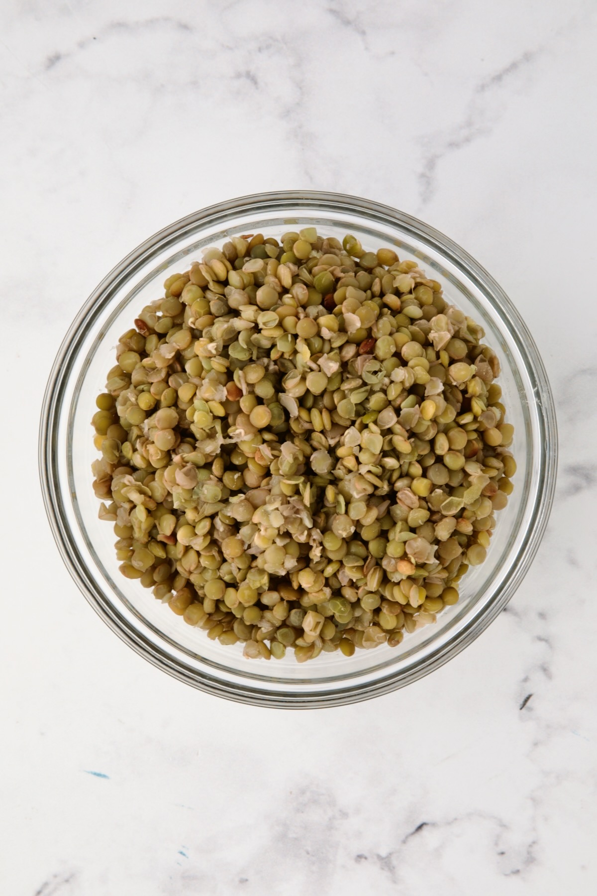 Cooked green lentils in glass bowl.