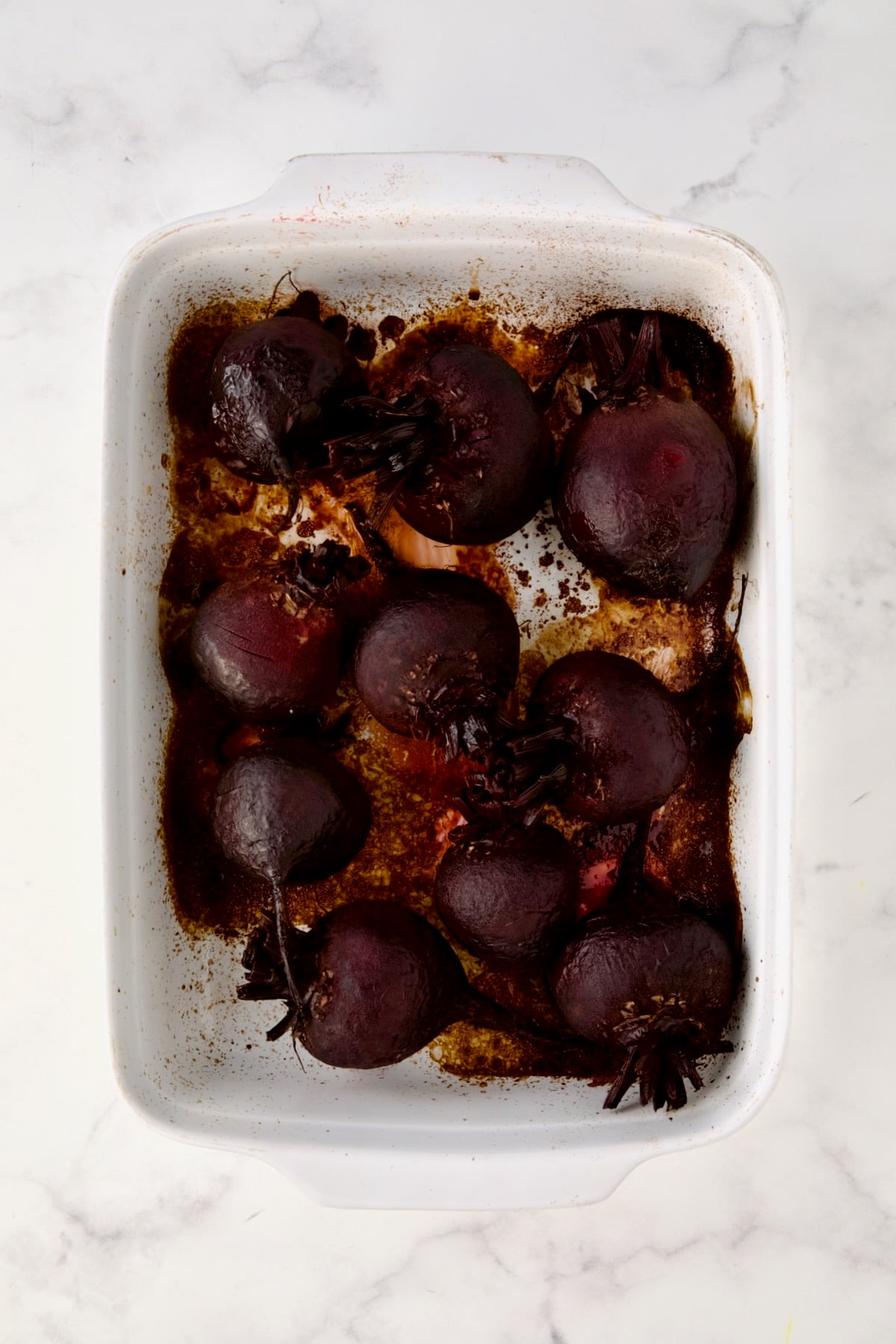 Roasted beets in white rectangular baking dish.
