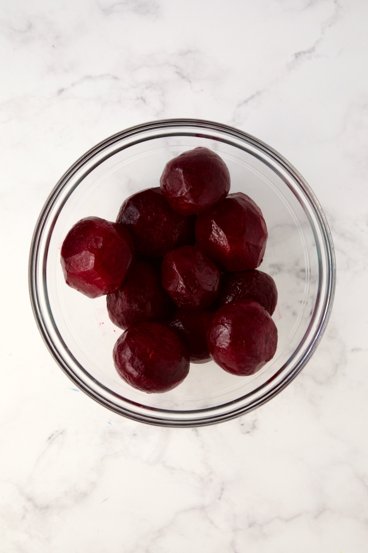 Peeled cooked beets in glass bowl.