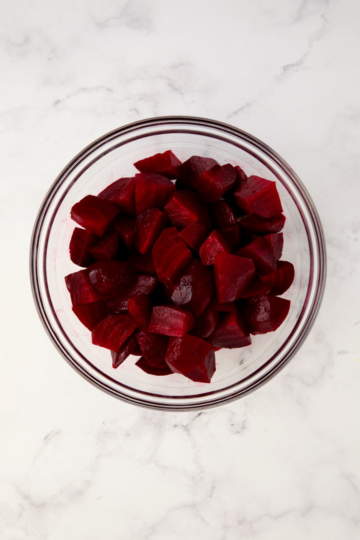 Cooked beets in glass bowl cut into chunks.