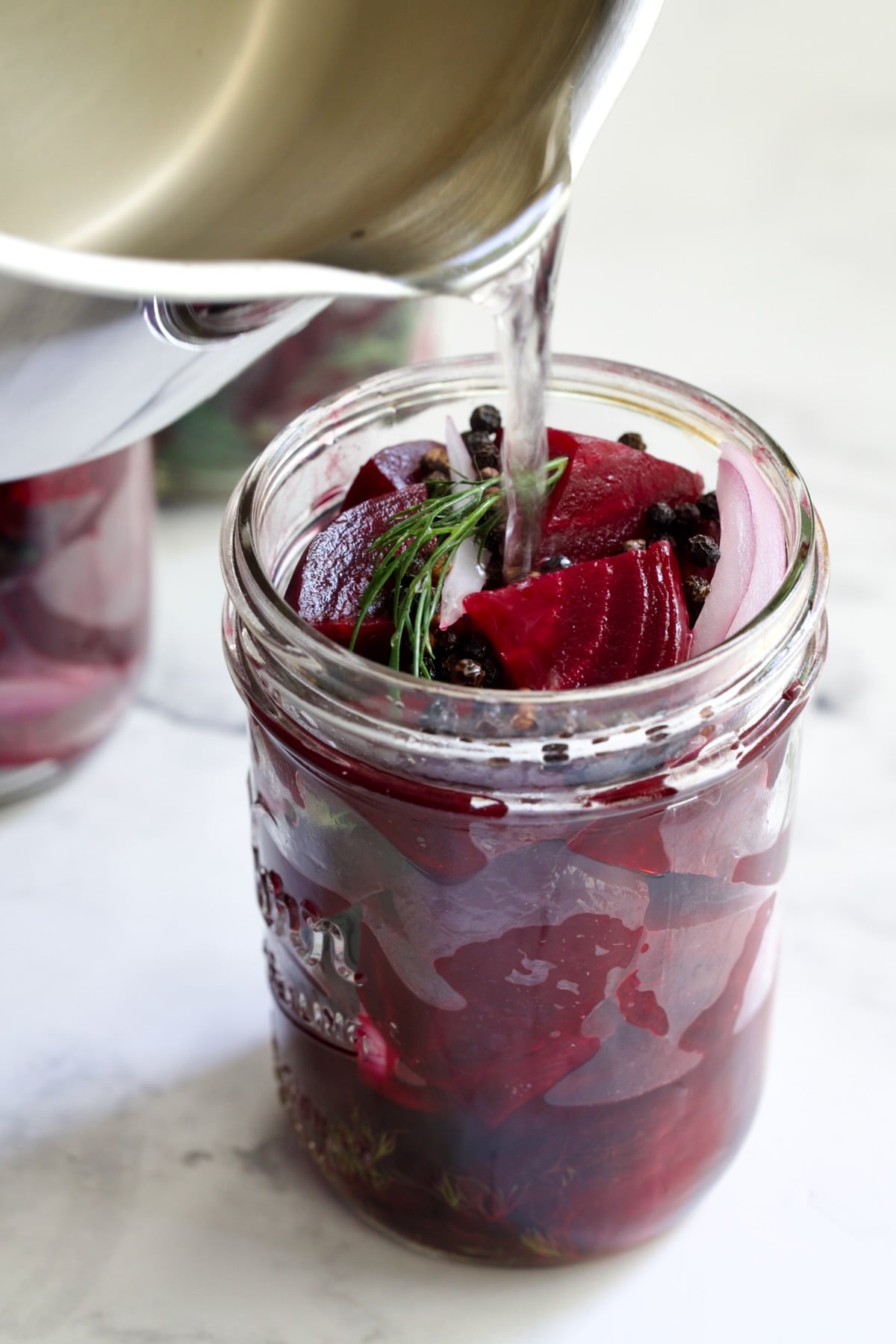 Brine being poured into beets in pint jar.