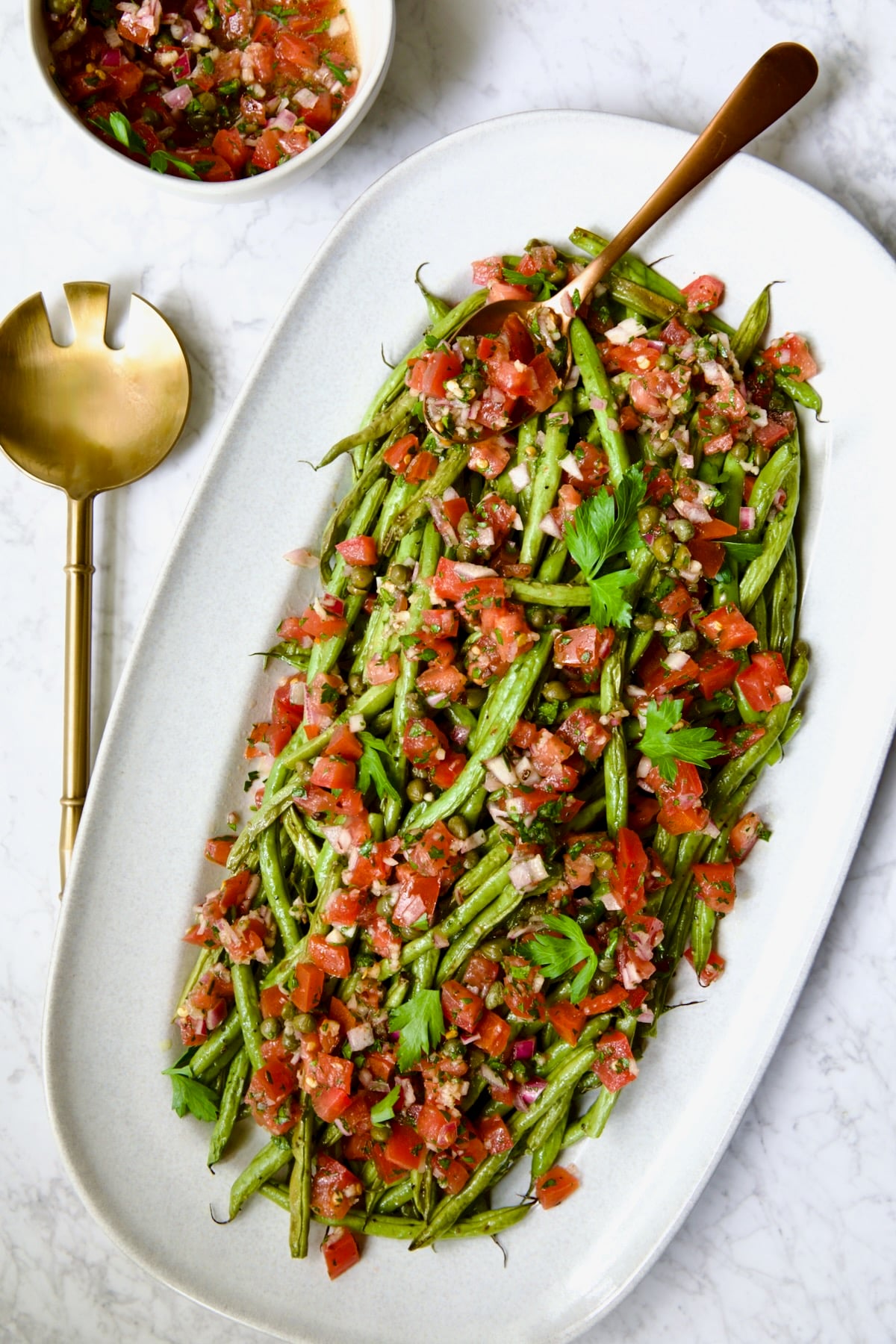 Roasted Green Beans with Tomato Caper Relish on oval white platter.