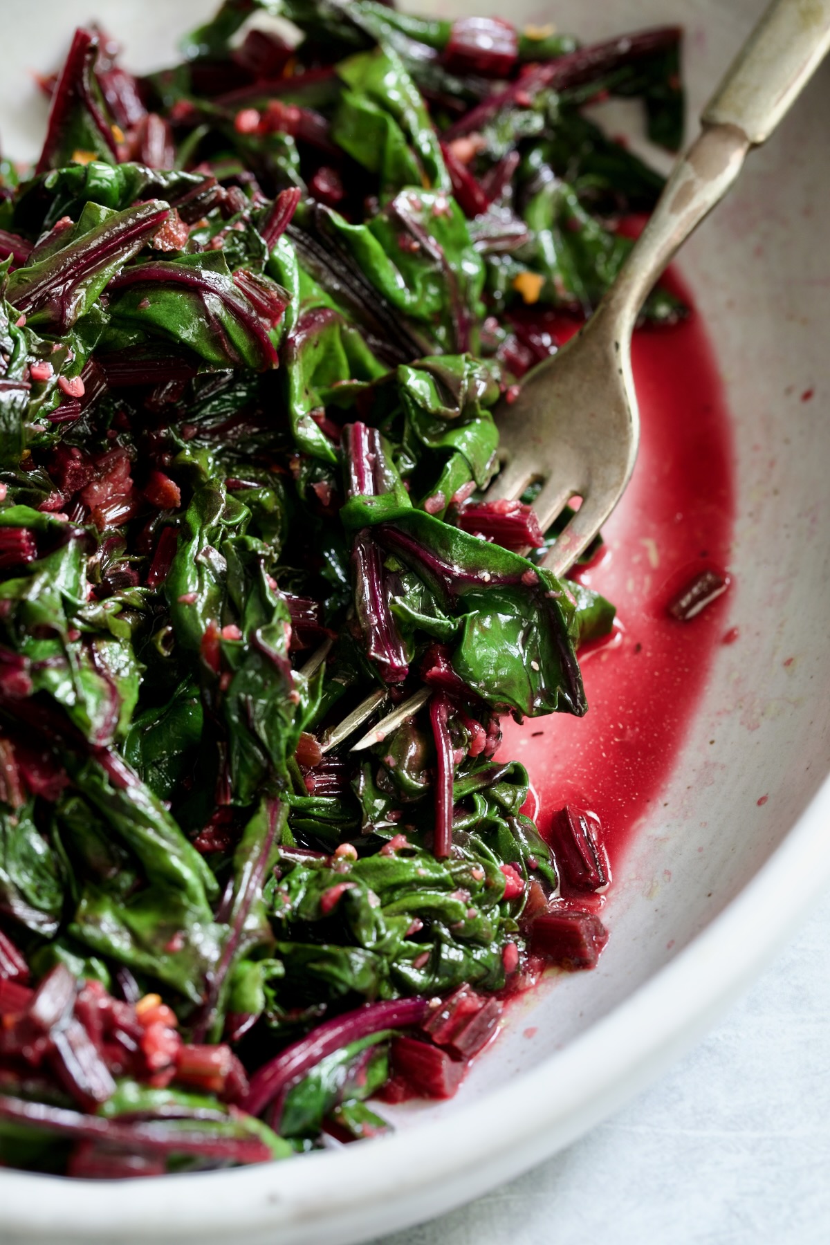 Sauteed Beet Greens in oval white serving bowl with fork.