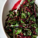 Sauteed Beet Greens in oval white serving bowl with fork.
