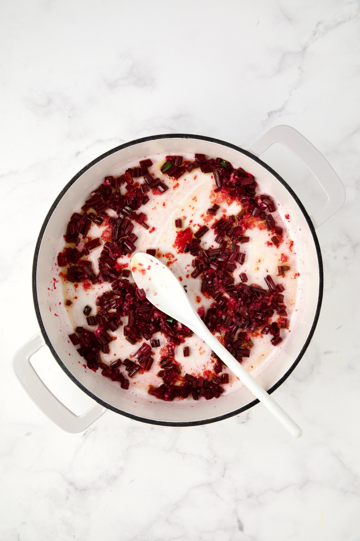 Sauteed beet stems in white enamel cast iron skillet.