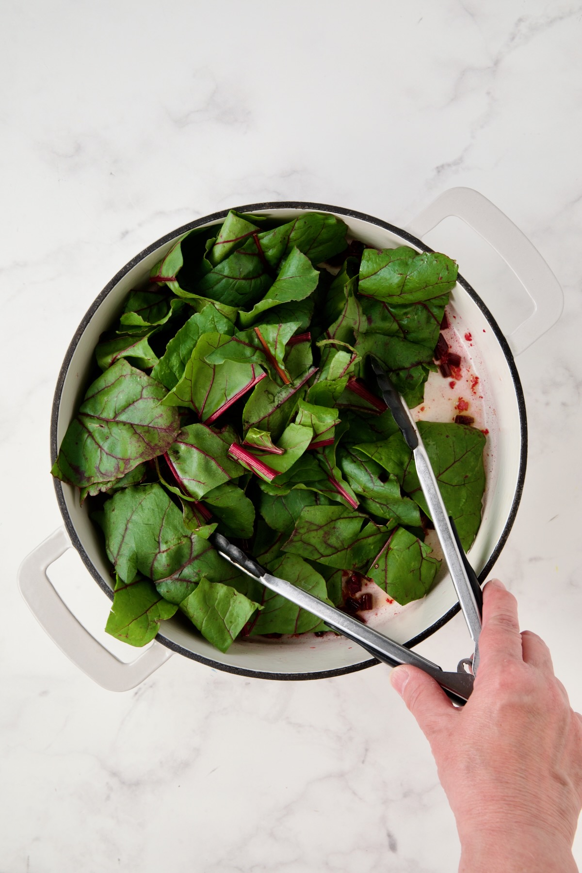 Coarsely chopped beet greens in white enamel cast iron skillet.