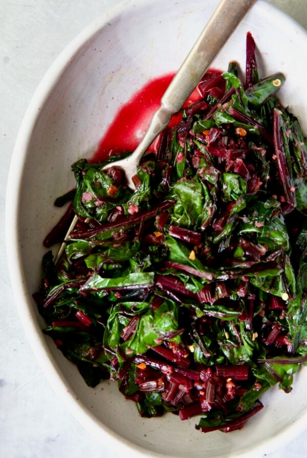 Sauteed Beet Greens in oval white serving bowl with fork.