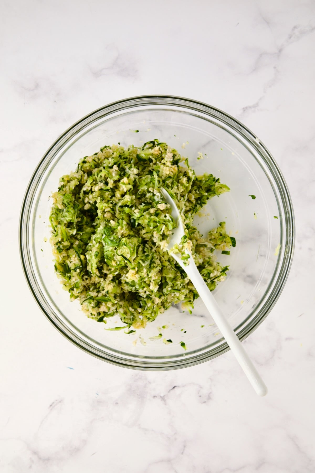 Ingredients for the zucchini crust in glass bowl after being mixed together.