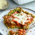 Piece of Zucchini Pizza Casserole on small plate with a piece on a fork.