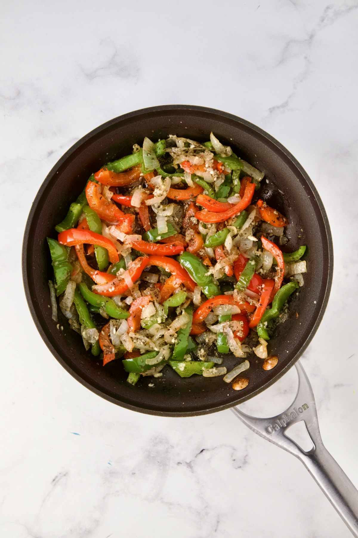 Cooked onions, red bell pepper, and green bell pepper in nonstick skillet.