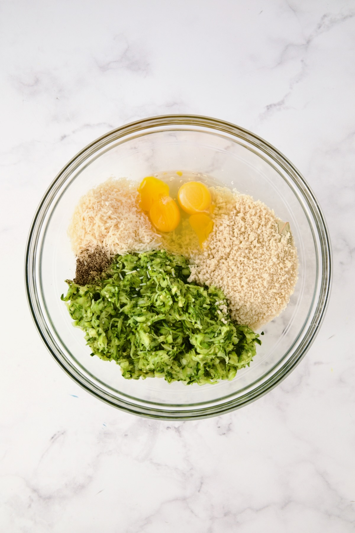 Ingredients for the zucchini crust in glass bowl before being mixed together.