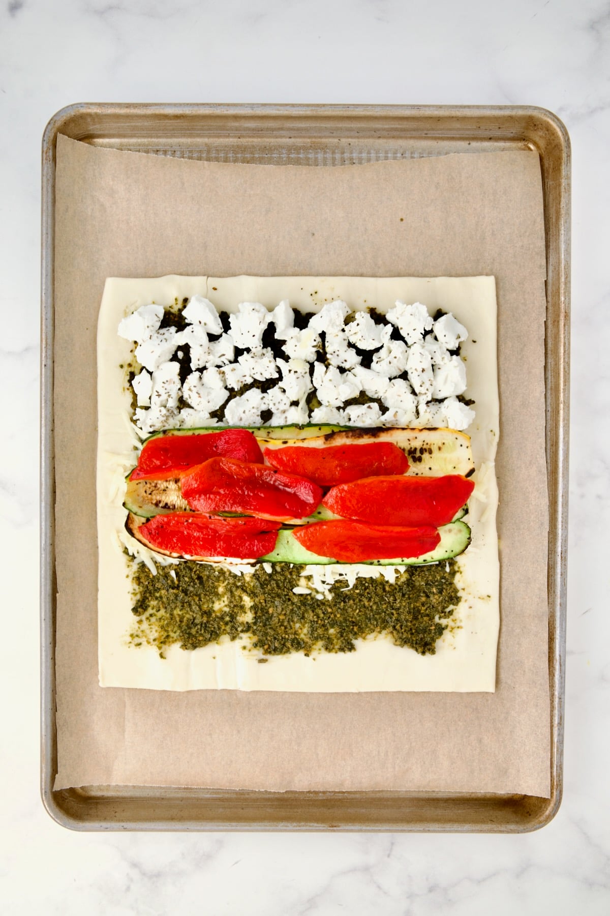 First layer of zucchini and yellow squash along with the red bell pepper placed over the shallot and cheese.