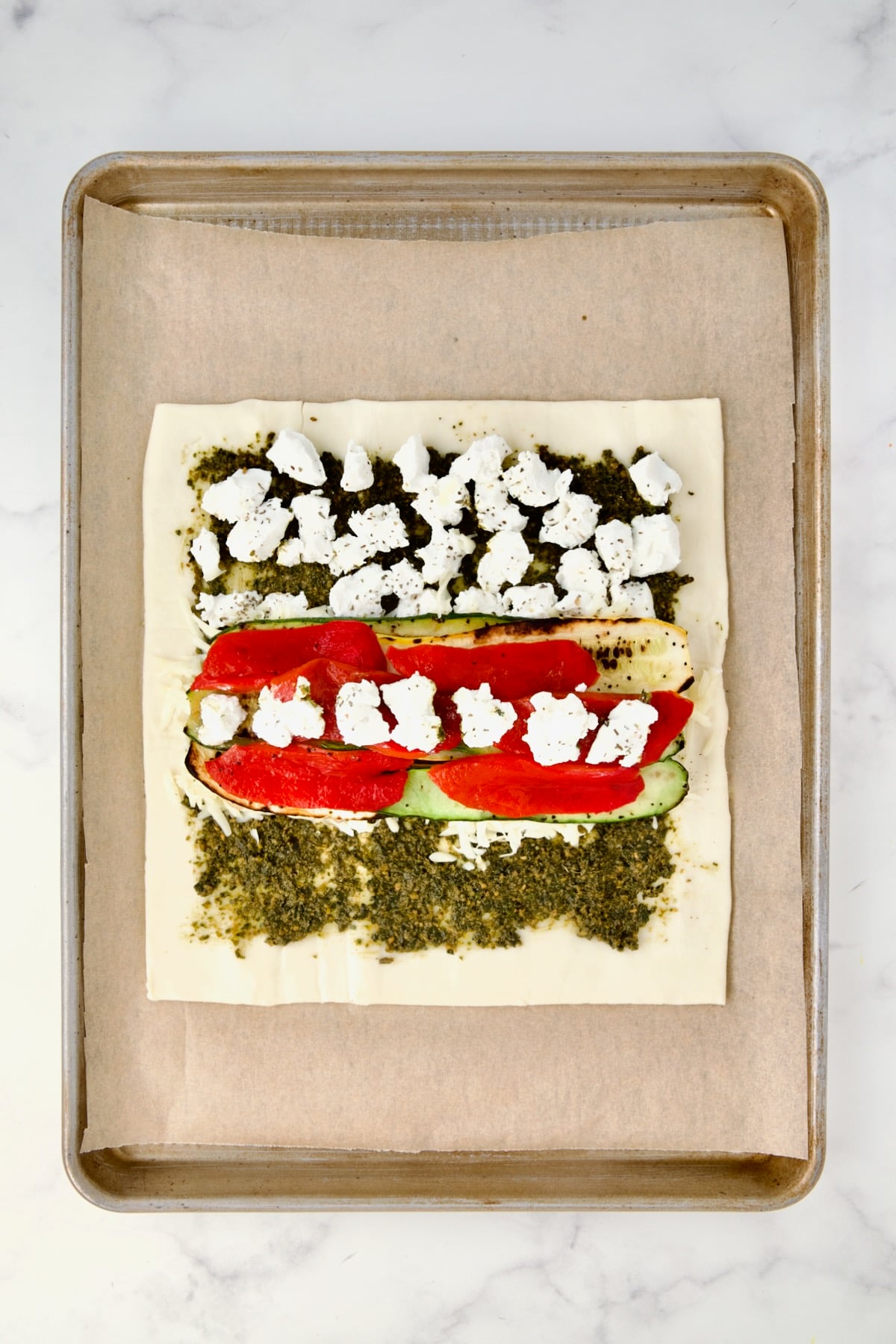 Goat cheese placed over the zucchini and red bell pepper.