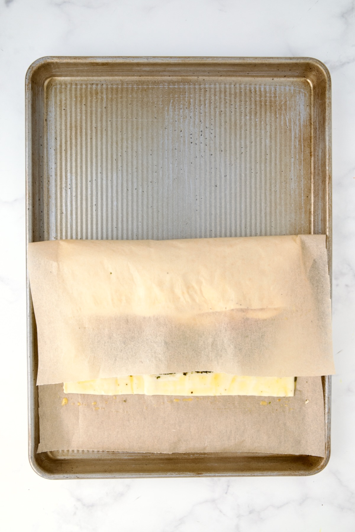 Strudel being folded with the help of the parchment paper.